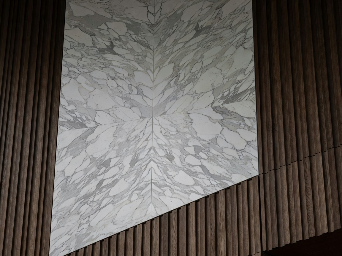Massive bookmatched Arabescato Corchia marble wall intersecting dark fluted thermal oak architectural paneling