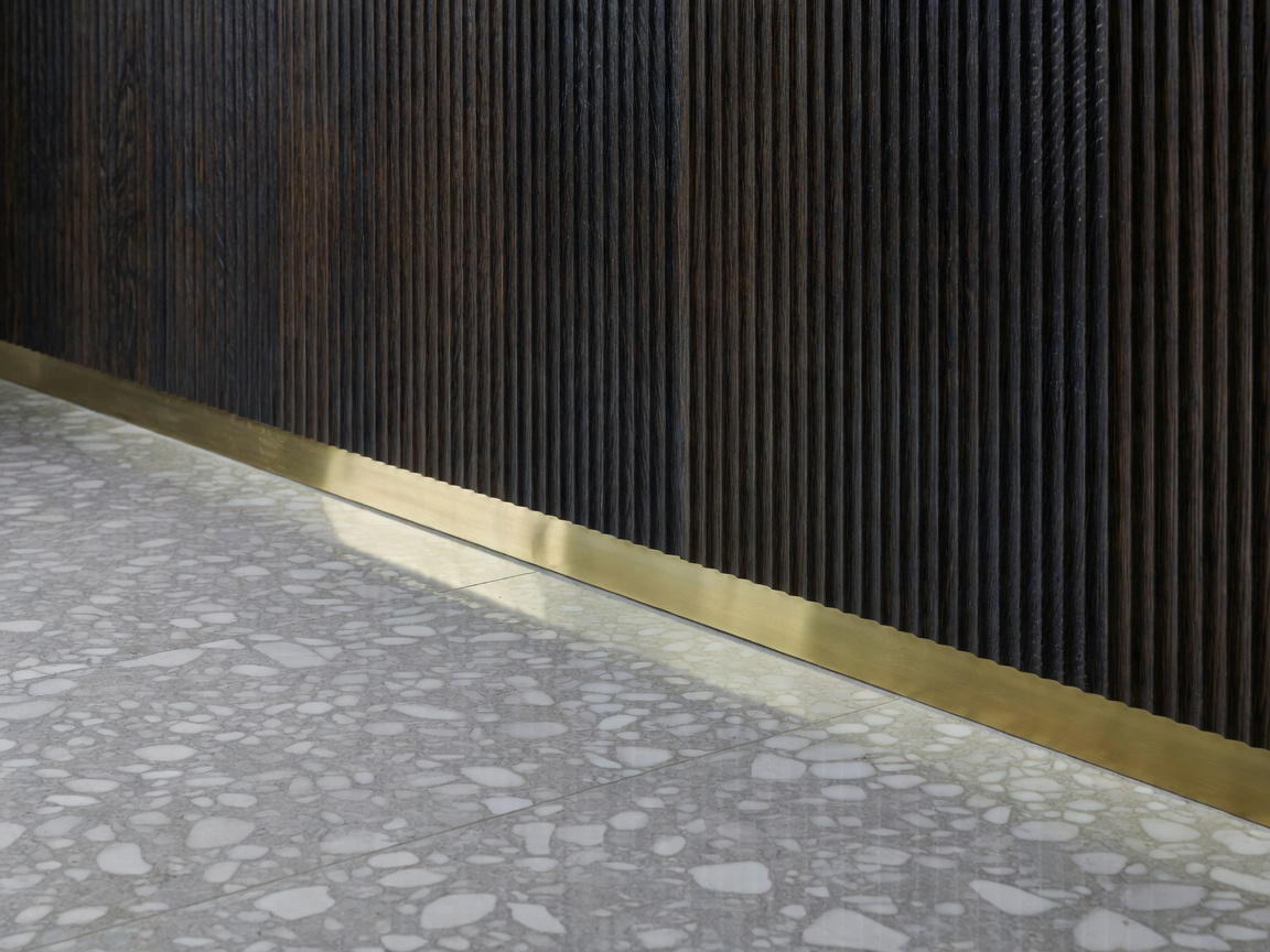 Polished Ceppo di Gre stone floor intersecting burnished brass trim and hand-fluted bog oak paneling